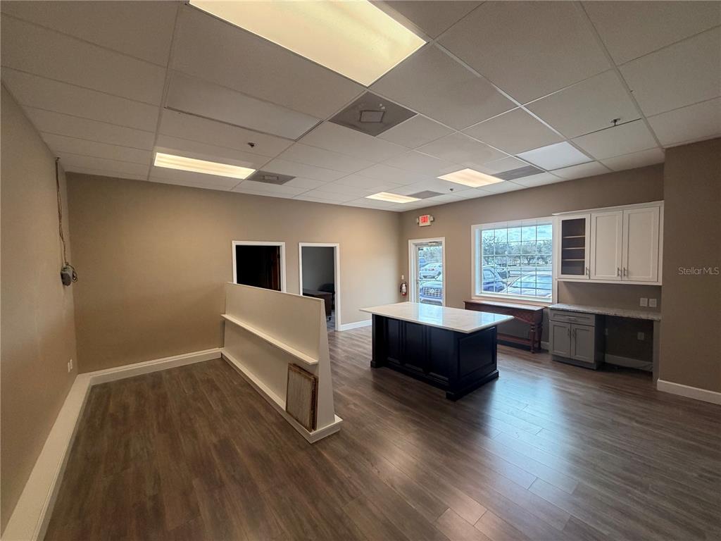 An office space features a central island, wood-look flooring, a drop ceiling, and cabinetry — 910 BELLE AVENUE UNIT 1140, WINTER SPRINGS, FL