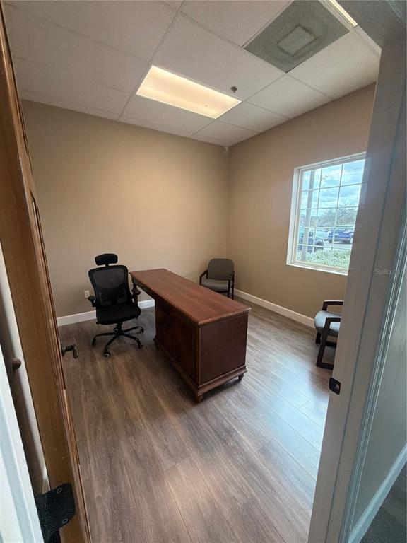 An office with wood-look flooring, a wooden desk, a black task chair, and two guest chairs — 910 BELLE AVENUE UNIT 1140, WINTER SPRINGS, FL