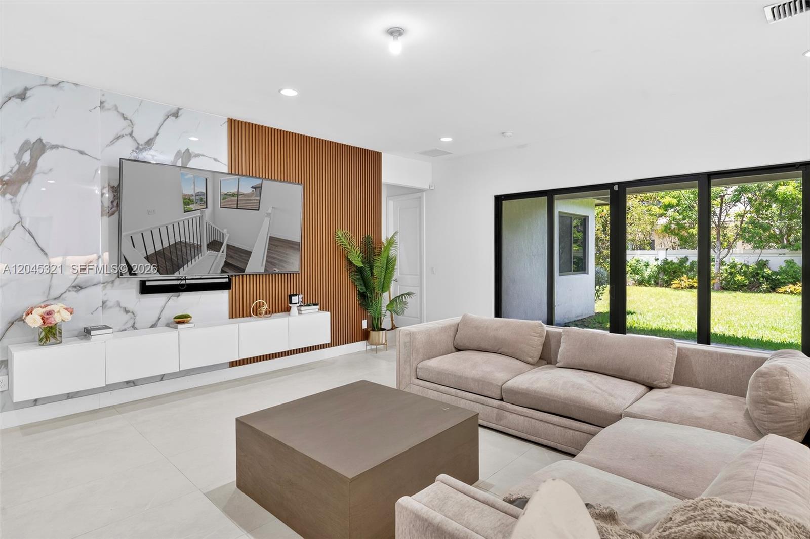 A modern living room features a marble and wood-slat accent wall with a mounted television — 4550 SW 178th Ave, Miramar FL 33029, MIRAMAR, FL