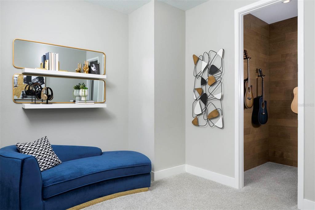 A blue chaise lounge sits in a room with wall shelves, decor, and a guitar closet — 12128 MEDITATION TRAIL, VENICE, FL