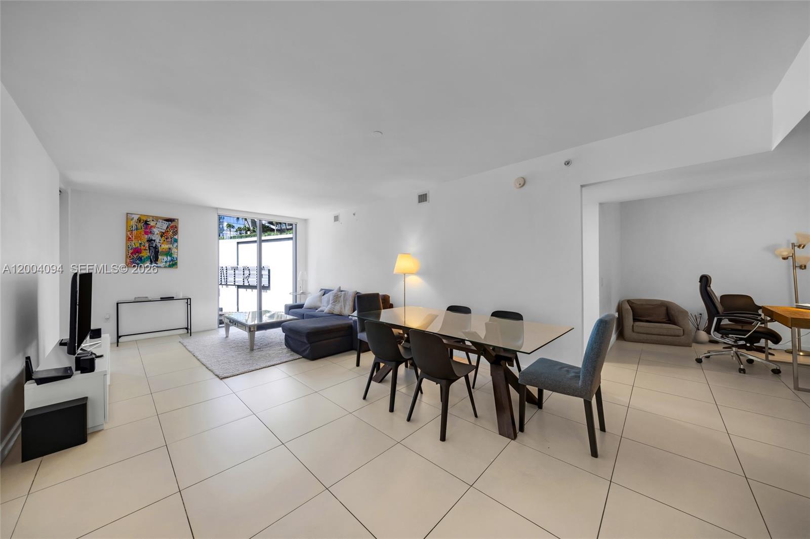 A bright, open-concept living and dining area features white tile floors and modern furnishings — 31 SE 6th St # 907, Miami FL 33131, MIAMI, FL