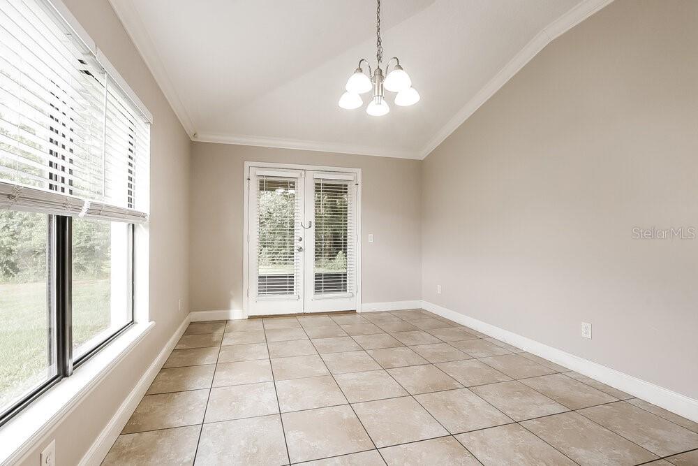 A bright dining room with tile flooring, a vaulted ceiling, and glass French doors — 348 ASHTON WOODS LANE, LEESBURG, FL