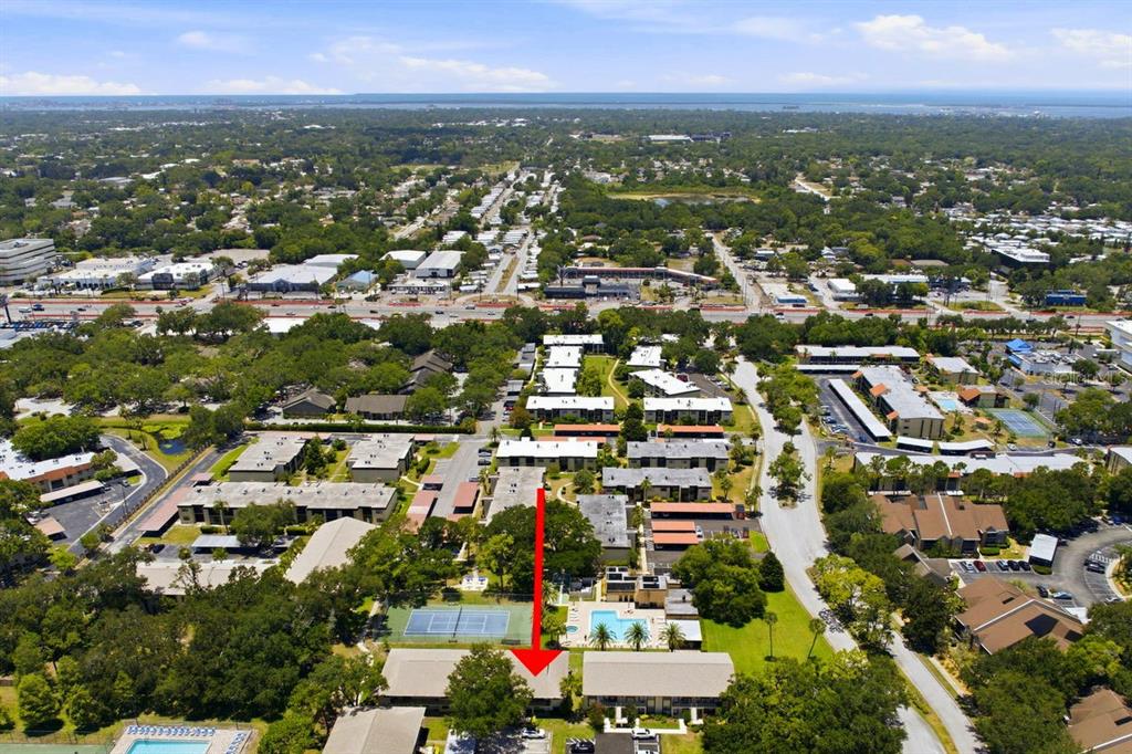 An aerial view shows a multi-story apartment complex with a red arrow pointing to a building — 2400 WINDING CREEK BOULEVARD UNIT 20A-109, CLEARWATER, FL