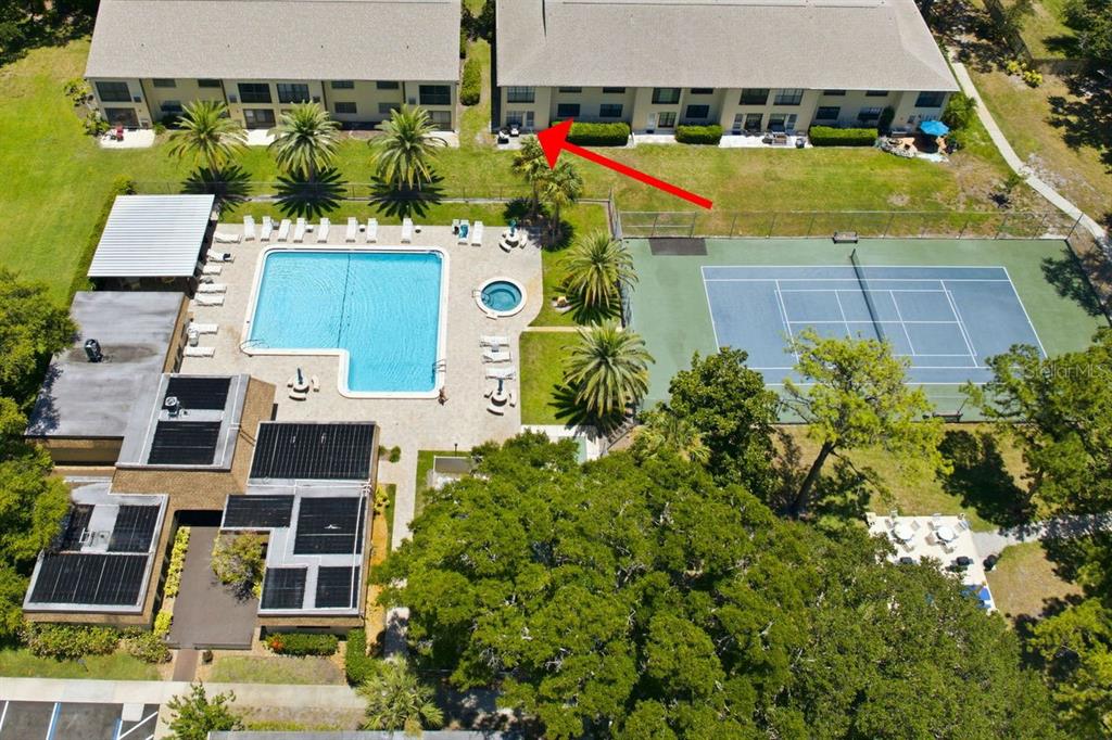 An aerial view shows a residential building next to a swimming pool and tennis court — 2400 WINDING CREEK BOULEVARD UNIT 20A-109, CLEARWATER, FL