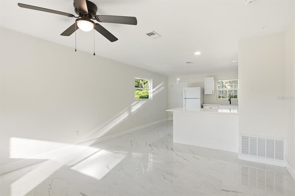 An open-concept kitchen and living area features white walls, marble-look tile flooring, and a ceiling fan — 708 PENNSYLVANIA AVENUE, CLEARWATER, FL