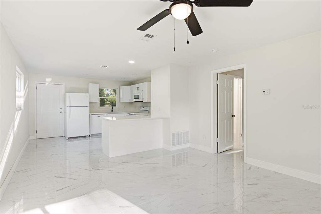 A bright kitchen and dining area features white cabinets, marble-look tile flooring, and a ceiling fan — 708 PENNSYLVANIA AVENUE, CLEARWATER, FL