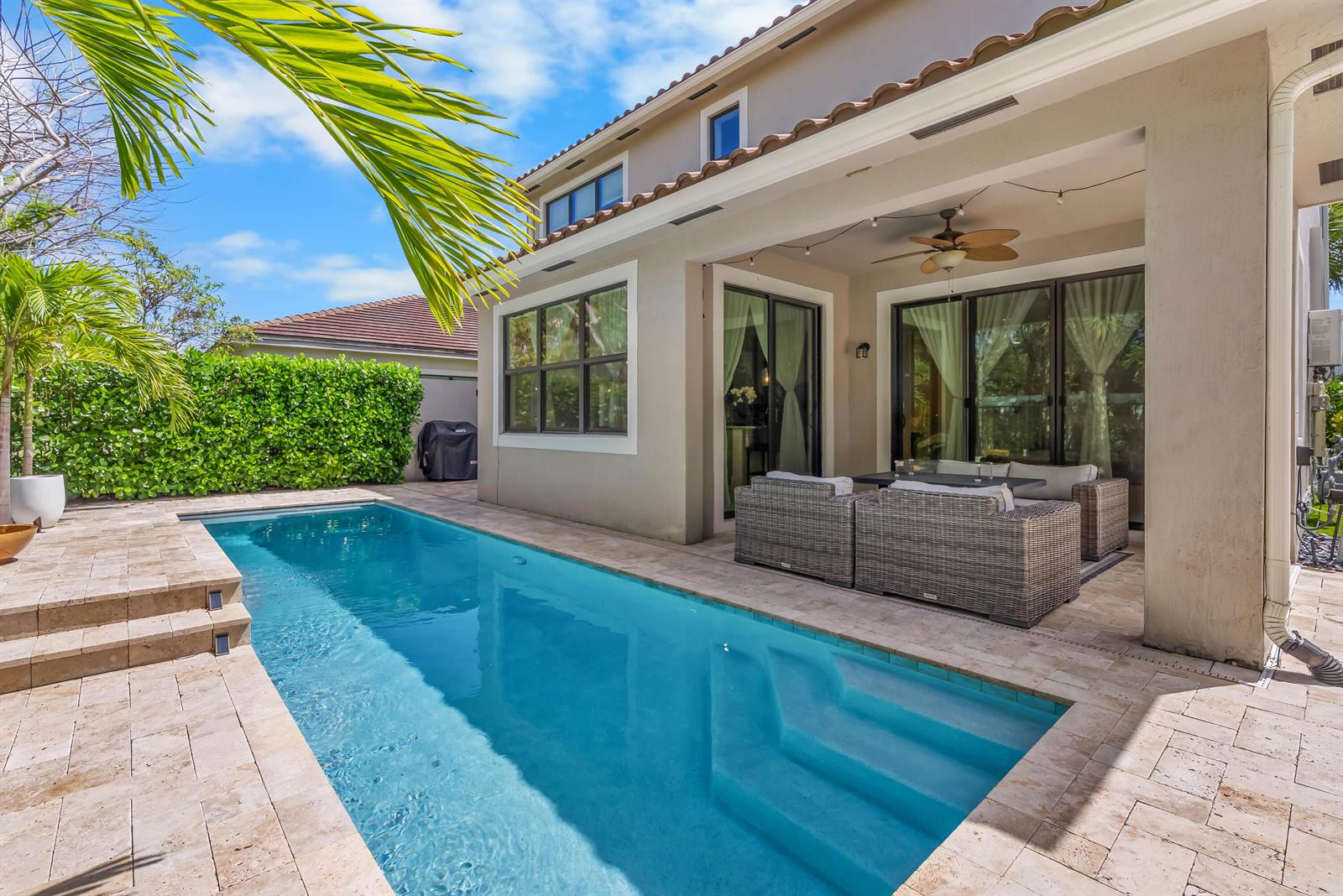 A rectangular swimming pool sits on a stone patio beside a covered outdoor seating area — 7241 Stella Lane, Lake Worth FL 33463, LAKE WORTH, FL