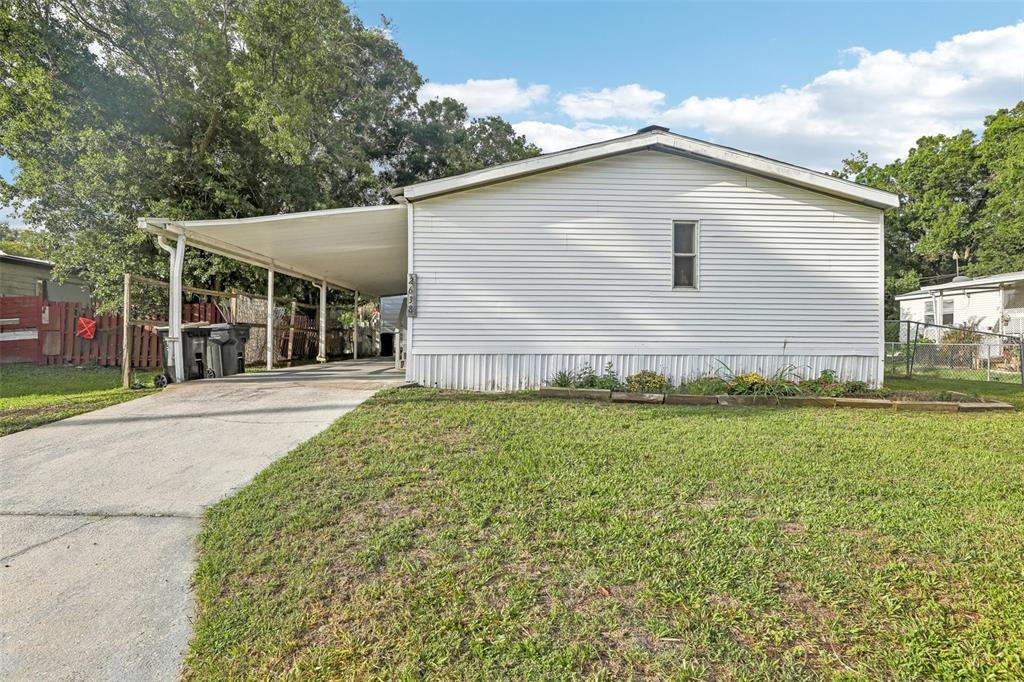 A white mobile home with a carport and a concrete driveway sits on a lawn — 2638 SEA OATS CIRCLE S, LAKELAND, FL