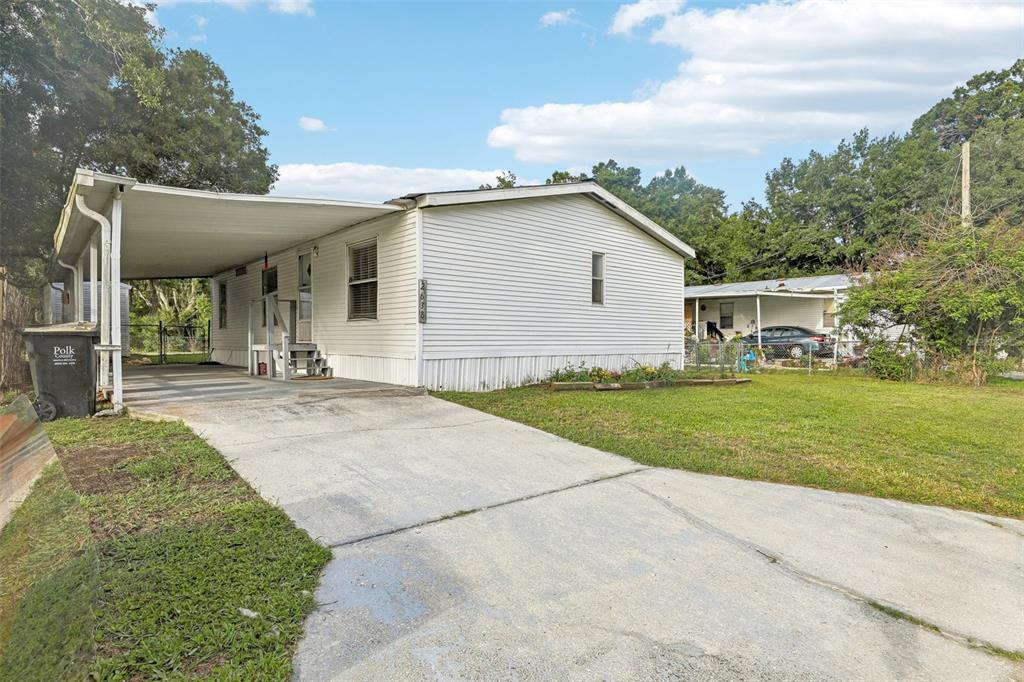 A white mobile home with a carport and concrete driveway sits on a grassy lot — 2638 SEA OATS CIRCLE S, LAKELAND, FL