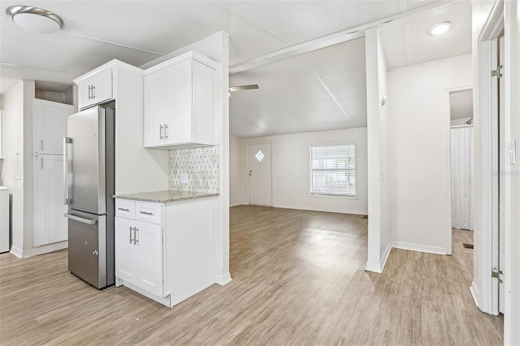 A kitchen with white cabinets and stainless steel appliances opens into a living area — 2638 SEA OATS CIRCLE S, LAKELAND, FL