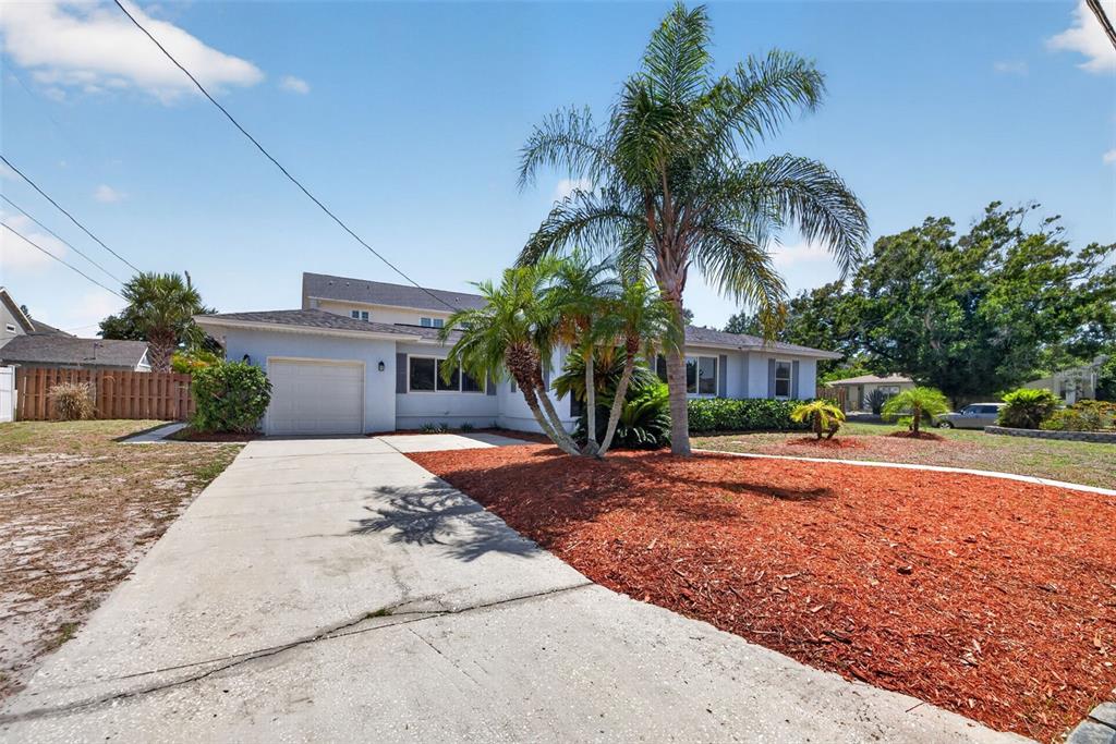 A light blue house with a concrete driveway and palm trees in the front yard — 1674 34TH AVENUE N, ST PETERSBURG, FL
