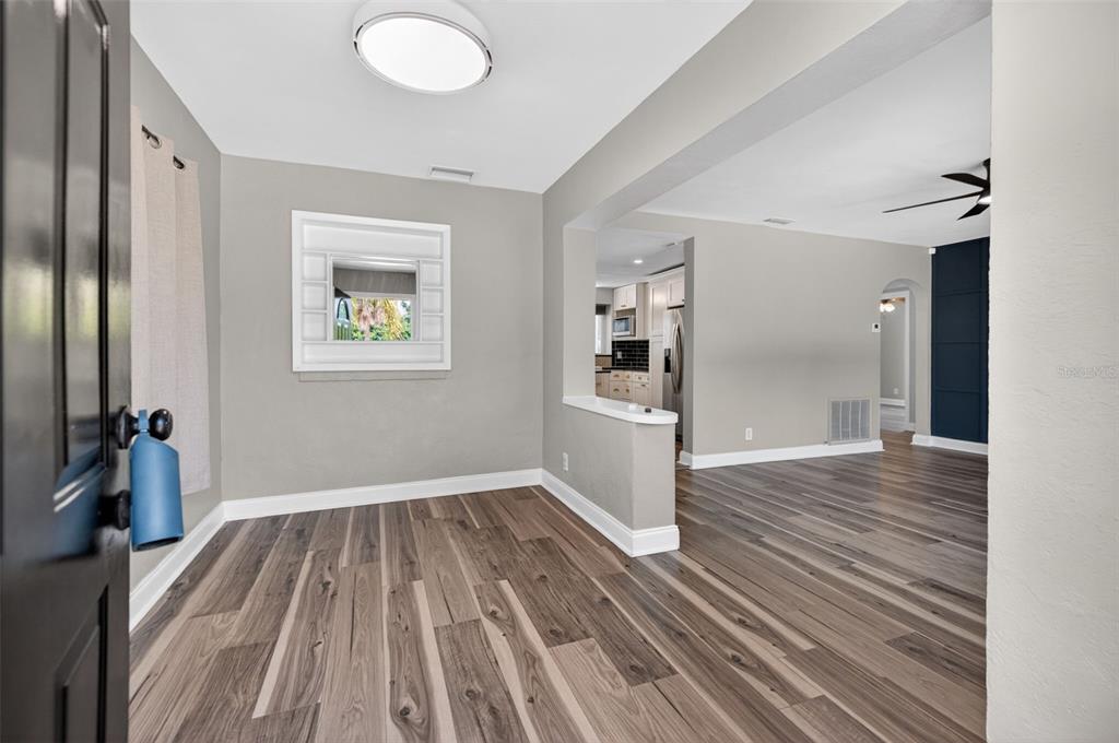 A view from a doorway into a dining area with wood-look flooring and a mirror — 1674 34TH AVENUE N, ST PETERSBURG, FL