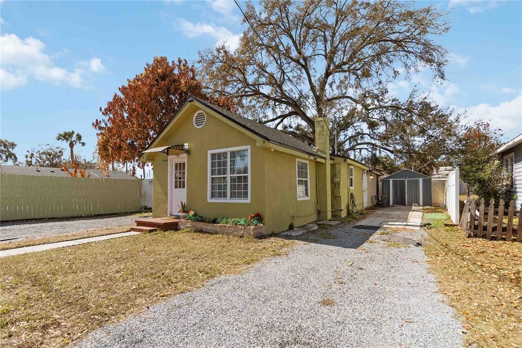 A small, yellow, single-story house with a gravel driveway and a detached metal shed — 710 BAY STREET, KISSIMMEE, FL