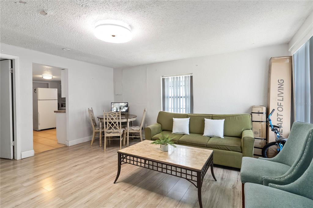 A living room features light wood-look flooring, a green sofa, and a small dining area — 710 BAY STREET, KISSIMMEE, FL