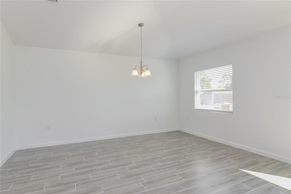 A dining room with white walls, gray wood-look tile flooring, and a hanging chandelier — 1251 AMAZON LANE, KISSIMMEE, FL