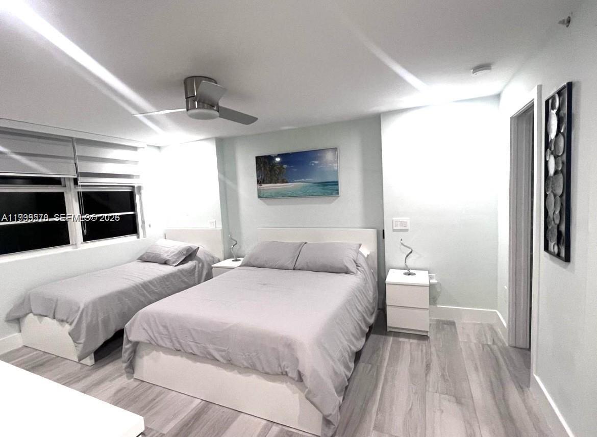 A bedroom features a queen bed, a twin bed, light wood flooring, and a ceiling fan — 6917 Collins Ave # 806, Miami Beach FL 33141, MIAMI BEACH, FL
