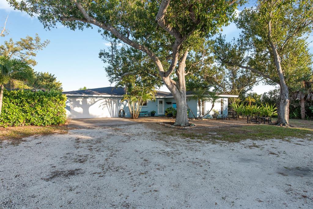 A light blue single-story house with a gravel driveway and large trees in the yard — 300 E BAY HEIGHTS AVENUE, ENGLEWOOD, FL