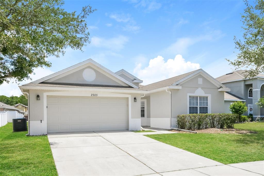 A single-story house with a two-car garage, light-colored stucco exterior, and a concrete driveway — 2925 WILLOW CREEK LANE, KISSIMMEE, FL