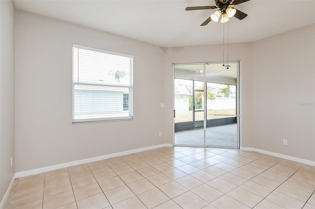 An empty room with beige tile flooring, a ceiling fan, and sliding glass patio doors — 2925 WILLOW CREEK LANE, KISSIMMEE, FL