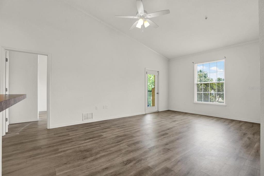 A living room with white walls, wood-look flooring, a ceiling fan, and a glass door — 10201 COURTNEY PALMS BOULEVARD UNIT 304, TAMPA, FL