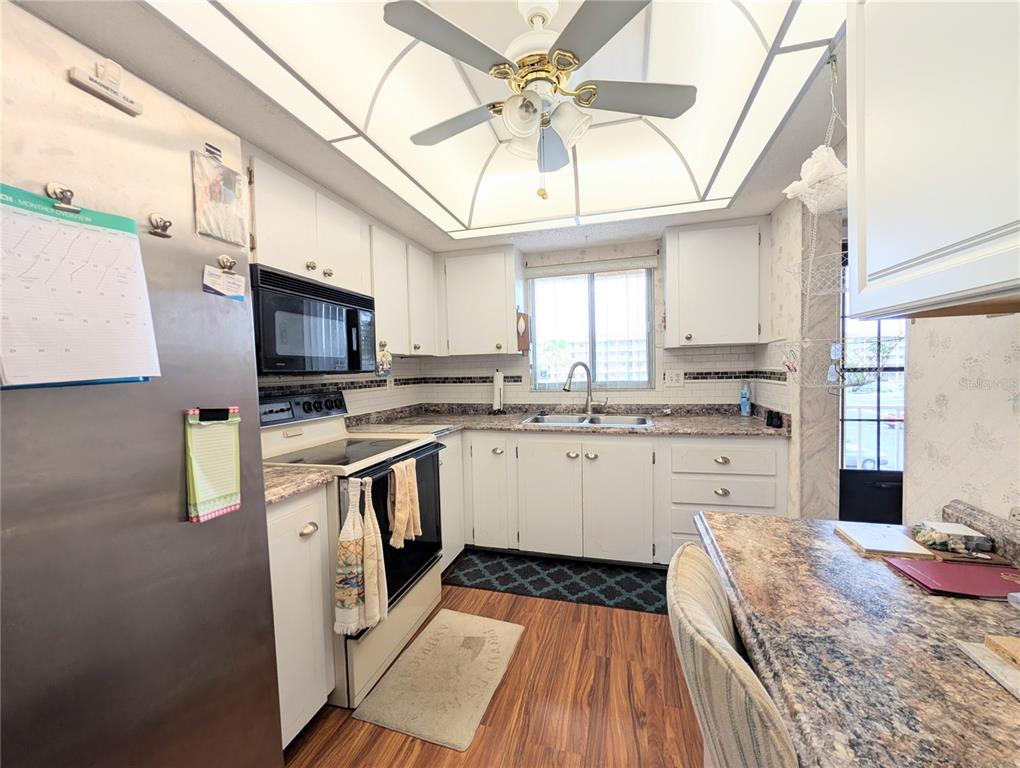 A kitchen features white cabinets, granite countertops, stainless steel appliances, and a ceiling fan — 3624 LAKE BAYSHORE DRIVE UNIT K-303, BRADENTON, FL