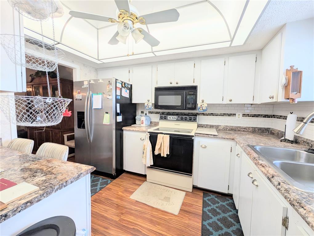 A kitchen features white cabinets, a stainless steel refrigerator, a range, and laminate countertops — 3624 LAKE BAYSHORE DRIVE UNIT K-303, BRADENTON, FL