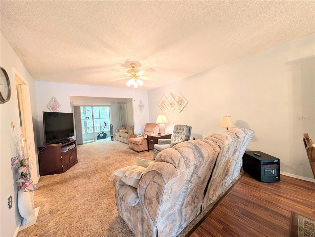 A living room features carpeted flooring, a ceiling fan, a television, and several armchairs — 3624 LAKE BAYSHORE DRIVE UNIT K-303, BRADENTON, FL