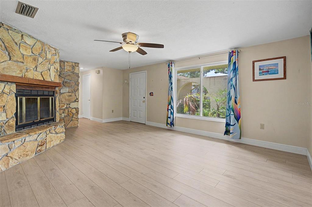 A living room features light wood-look flooring, a stone fireplace, and a large window — 1100 PERSIMMON DRIVE, PALM HARBOR, FL