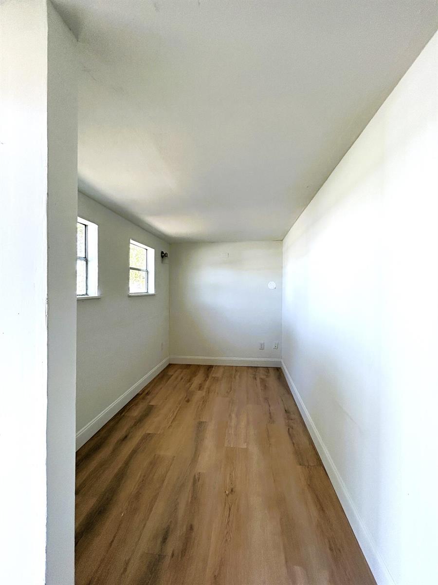 An empty room with light-colored walls and wood-look flooring features two windows on the left — 2024 Dixie Avenue, FL 32726, FL