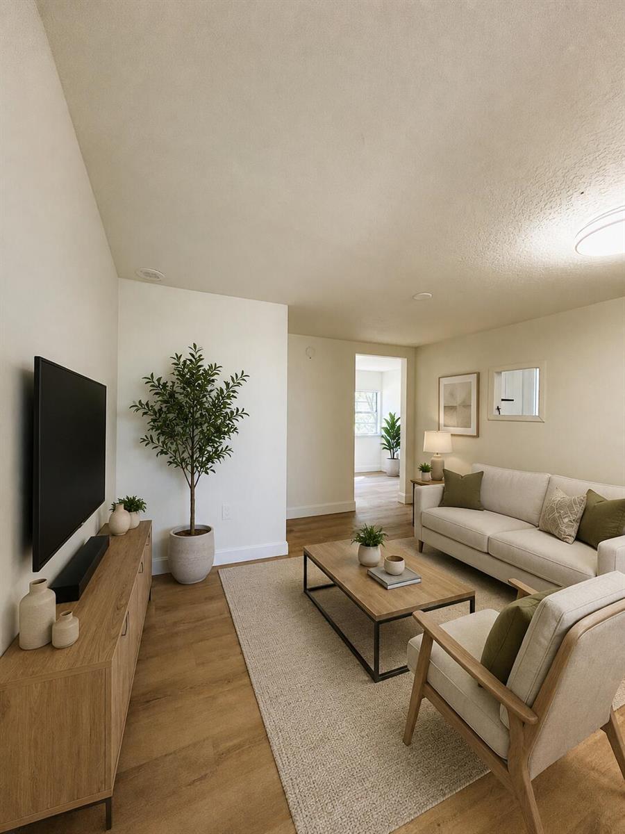 A living room features a television, light wood media console, sofa, armchair, and potted plant — 2024 Dixie Avenue, FL 32726, FL