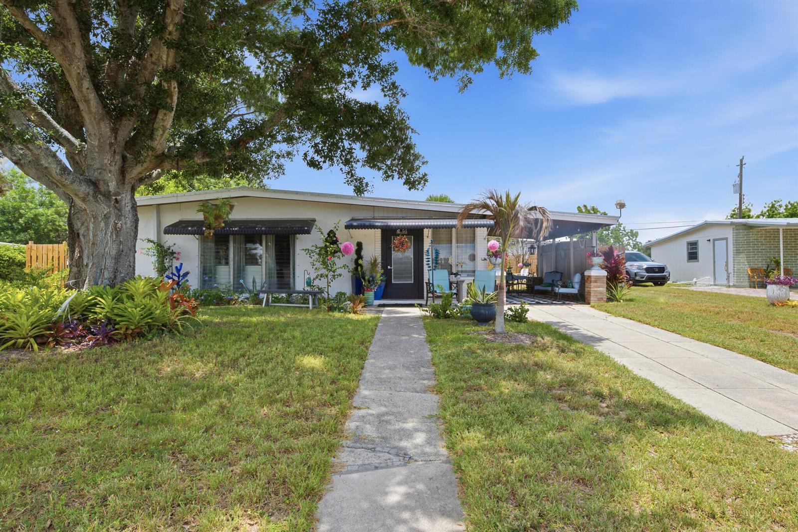 A single-story house with a large tree, a concrete walkway, and a carport — 54 20th Lane SW, Vero Beach FL 32962, VERO BEACH, FL