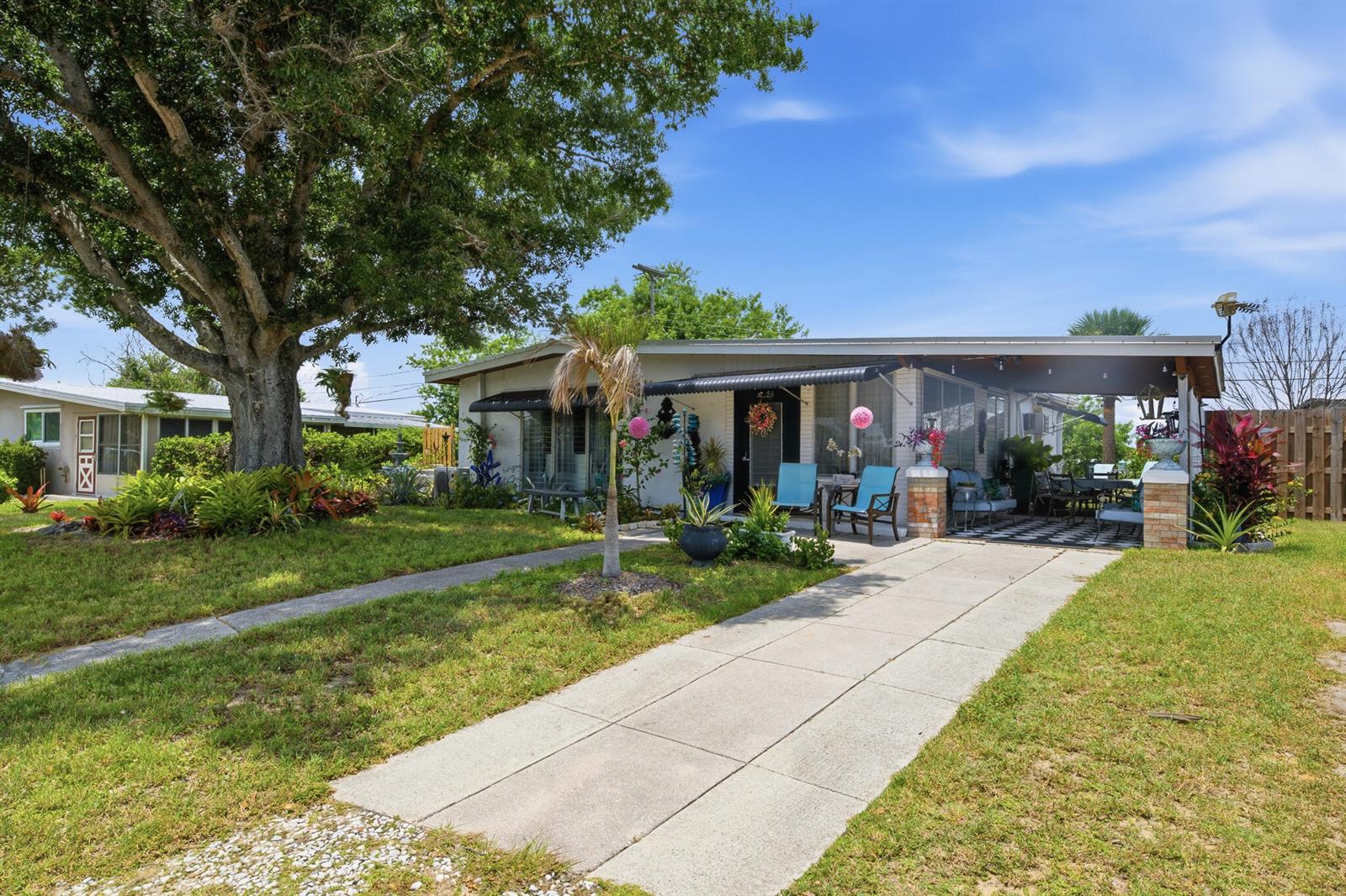 A single-story house with a large tree, a concrete driveway, and a covered front patio — 54 20th Lane SW, Vero Beach FL 32962, VERO BEACH, FL