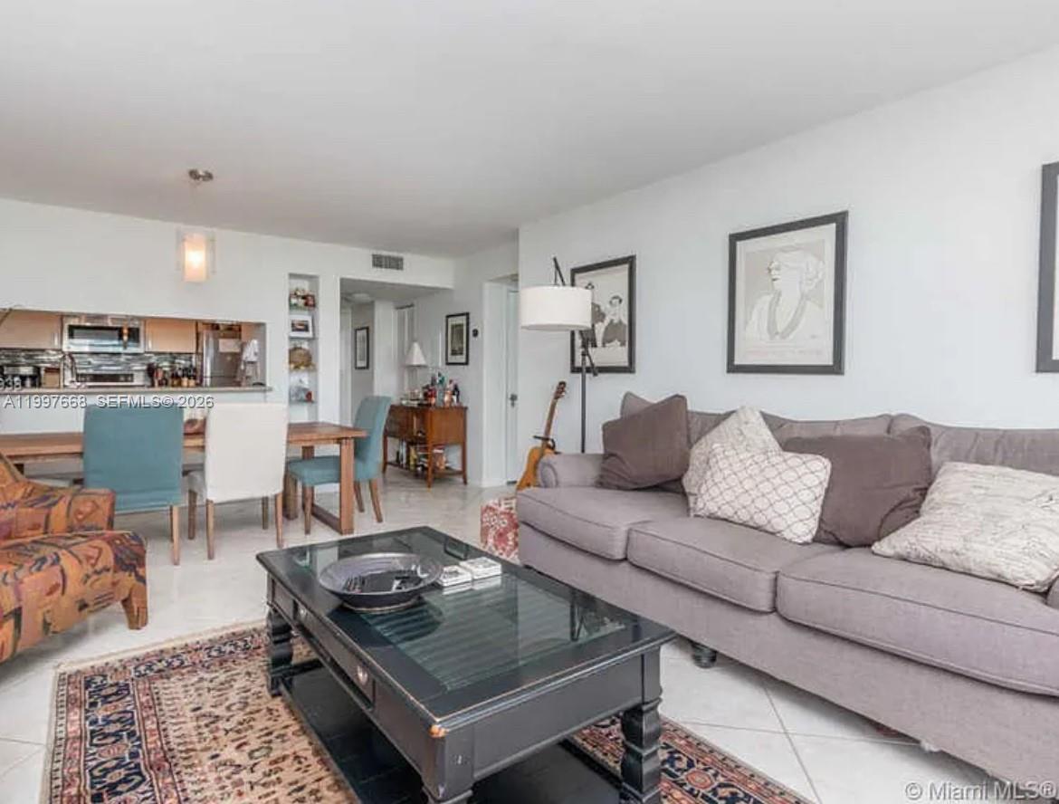 A living room with a grey sofa, glass coffee table, and an adjacent dining area — 600 NE 36th St # 1006, Miami FL 33137, MIAMI, FL