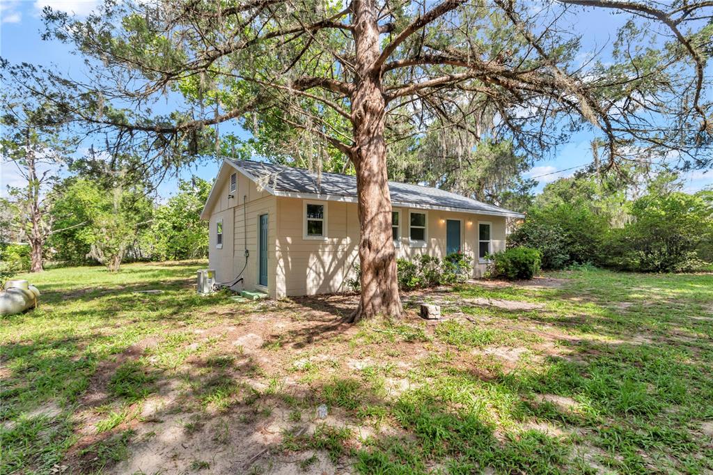 A light-colored, single-story house sits on a grassy lot beneath a large, mossy tree — 658 NE 39TH COURT, OCALA, FL