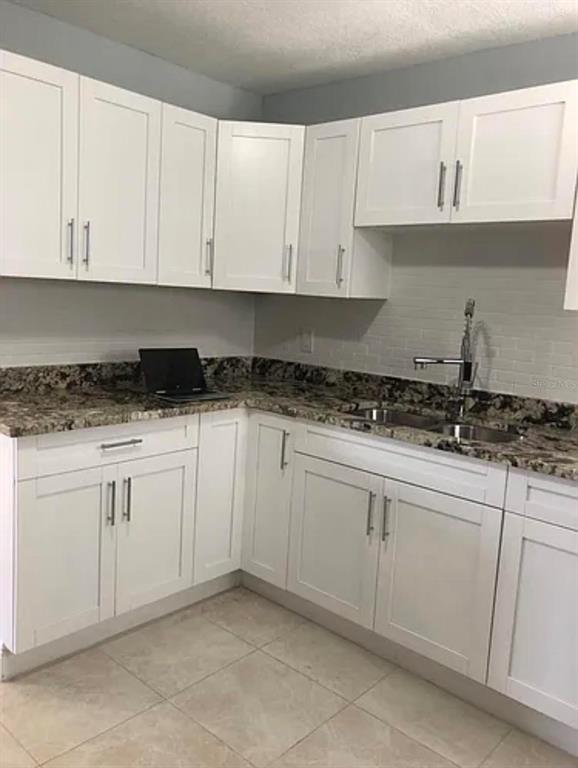 A kitchen with white cabinets, granite countertops, a stainless steel sink, and light tile flooring — 3001 E MCBERRY STREET, TAMPA, FL