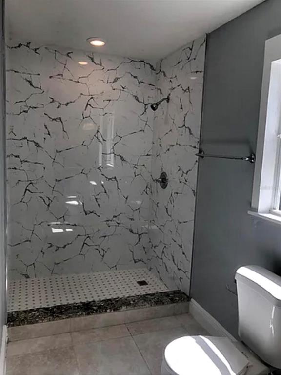 A bathroom features a walk-in shower with marble-patterned walls, a tiled floor, and a toilet — 3001 E MCBERRY STREET, TAMPA, FL
