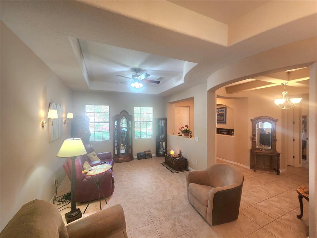 A living room features tile flooring, a tray ceiling with a fan, and arched doorways — 4061 ASHEVILLE LANE, ST CLOUD, FL