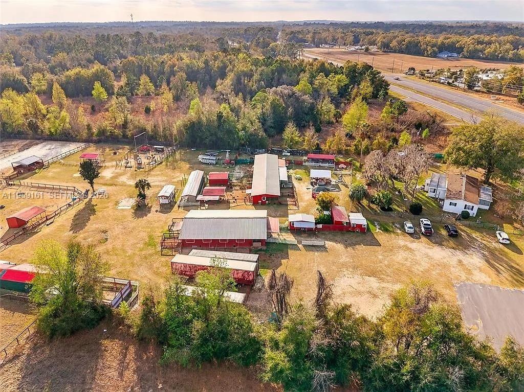 An aerial view shows a rural property with multiple red barns, outbuildings, and fenced paddocks — 11150 W Highway 40, Ocala FL 34482-6840, OCALA, FL