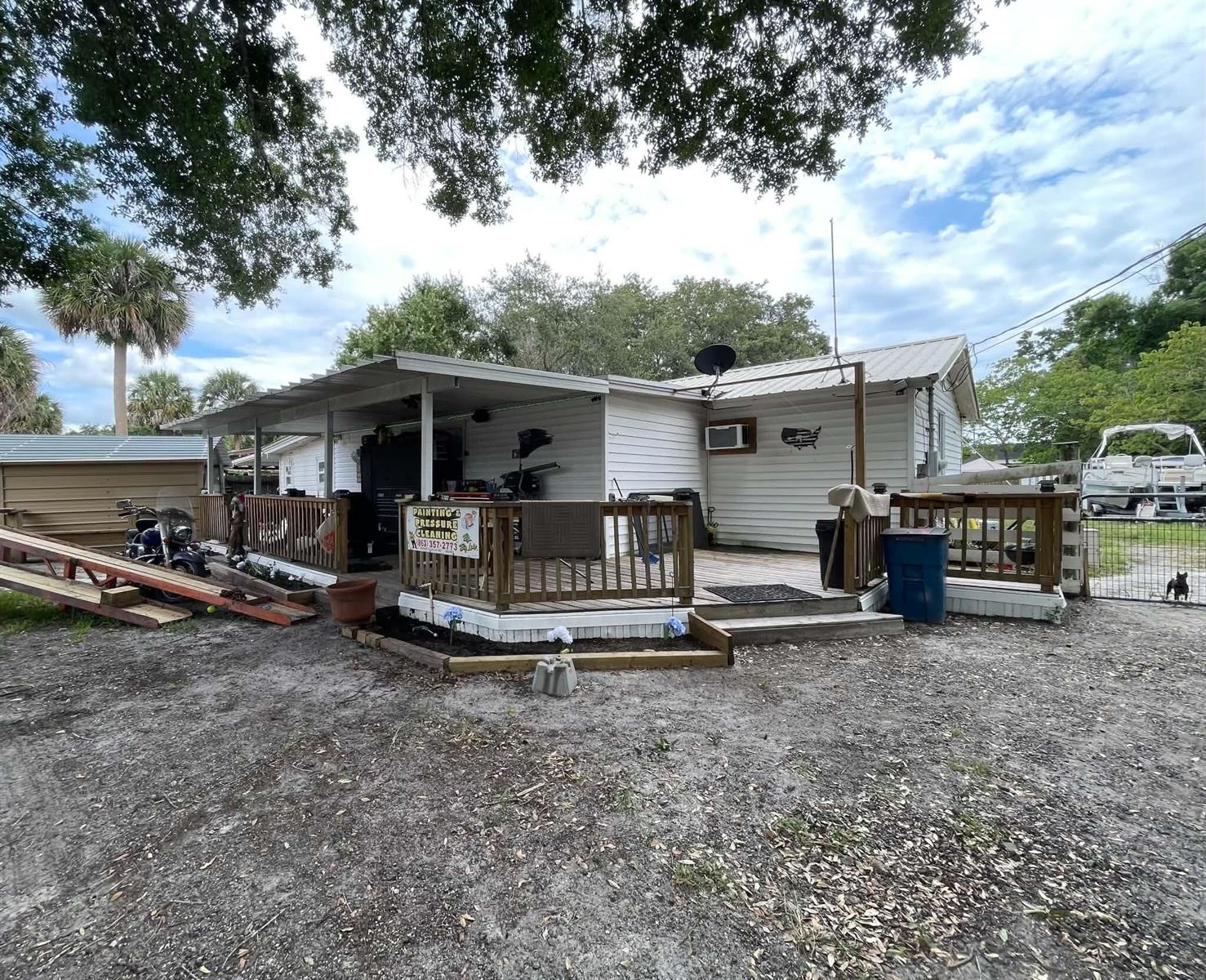 A white house with a large wooden deck, a metal roof, and a carport — 1111 NW 3rd Street, Okeechobee FL 34972, OKEECHOBEE, FL