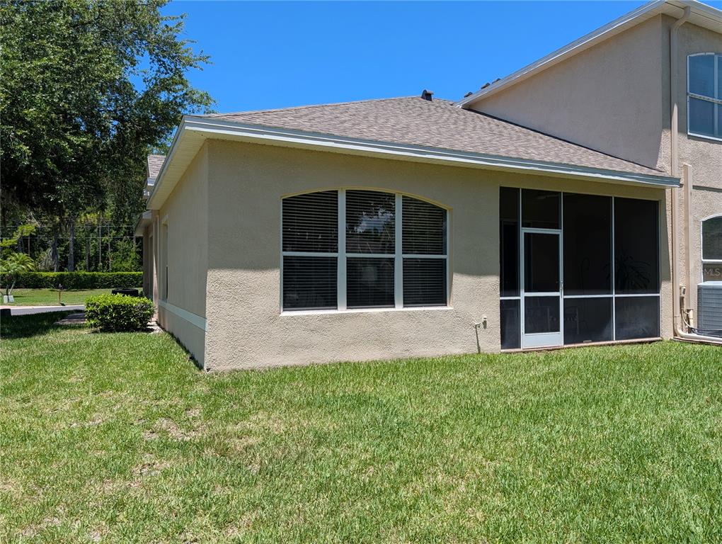 The exterior of a tan stucco house features a screened-in porch and arched windows — 7419 WIMPOLE DRIVE, NEW PORT RICHEY, FL