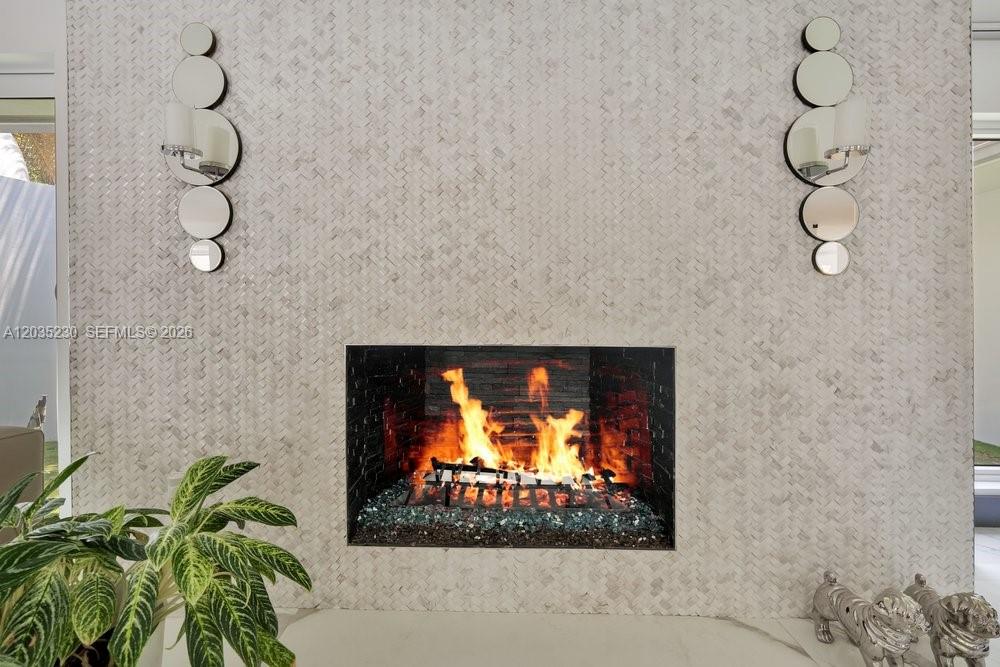 A fireplace with a textured tile surround and two vertical wall sconces — 6460 SW 133rd Dr, Pinecrest FL 33156, PINECREST, FL