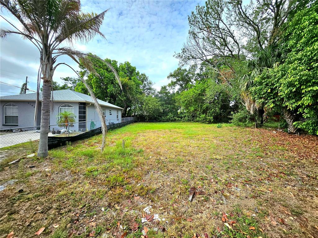 A vacant, grassy lot sits next to a single-story house with a palm tree — 5106 16TH AVENUE S, GULFPORT, FL
