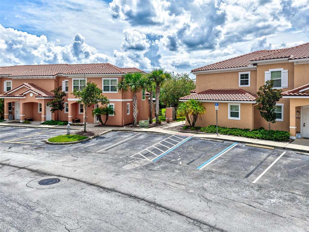 An exterior view of two-story stucco townhomes with tile roofs and a paved parking lot — 2668 CORVETTE LANE, KISSIMMEE, FL