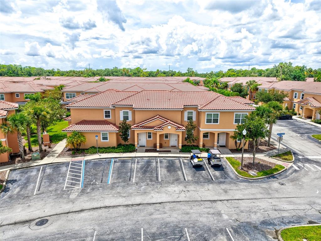An aerial view shows a two-story tan apartment building with a tiled roof and parking — 2668 CORVETTE LANE, KISSIMMEE, FL