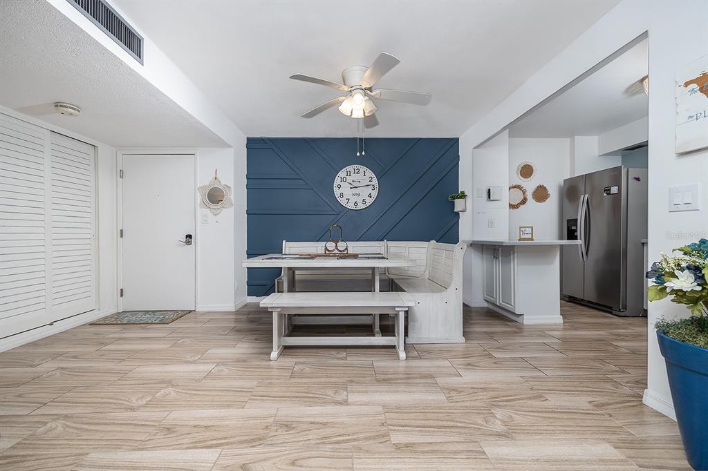 A dining area features a blue accent wall, a white corner bench, and wood-look tile flooring — 2800 N ATLANTIC AVENUE UNIT 1401, DAYTONA BEACH, FL