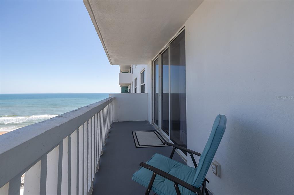 A balcony with a railing overlooks the ocean and features a blue patio chair — 2800 N ATLANTIC AVENUE UNIT 1401, DAYTONA BEACH, FL