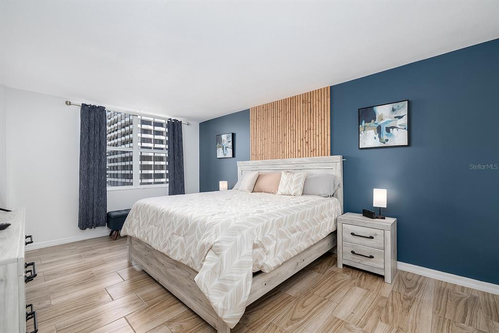 A bedroom features a bed with a wood-slat accent wall and blue painted walls — 2800 N ATLANTIC AVENUE UNIT 1401, DAYTONA BEACH, FL