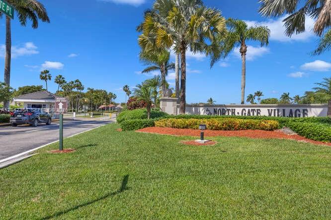 The entrance to North Gate Village features a gated guardhouse, palm trees, and landscaping — 2405 SE 5th Ct, Homestead FL 33033, HOMESTEAD, FL