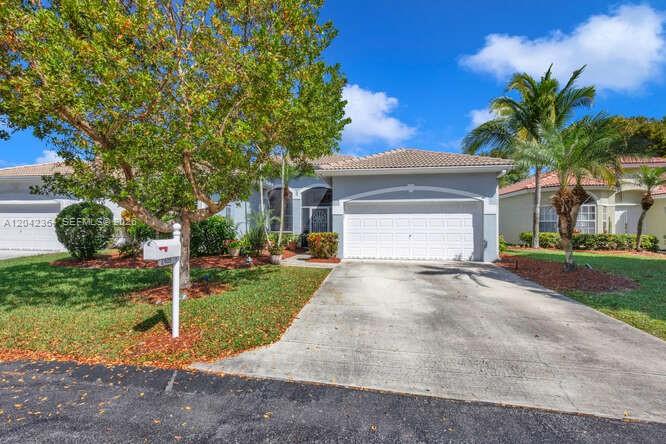 A single-story suburban house with a two-car garage, a concrete driveway, and palm trees — 2405 SE 5th Ct, Homestead FL 33033, HOMESTEAD, FL