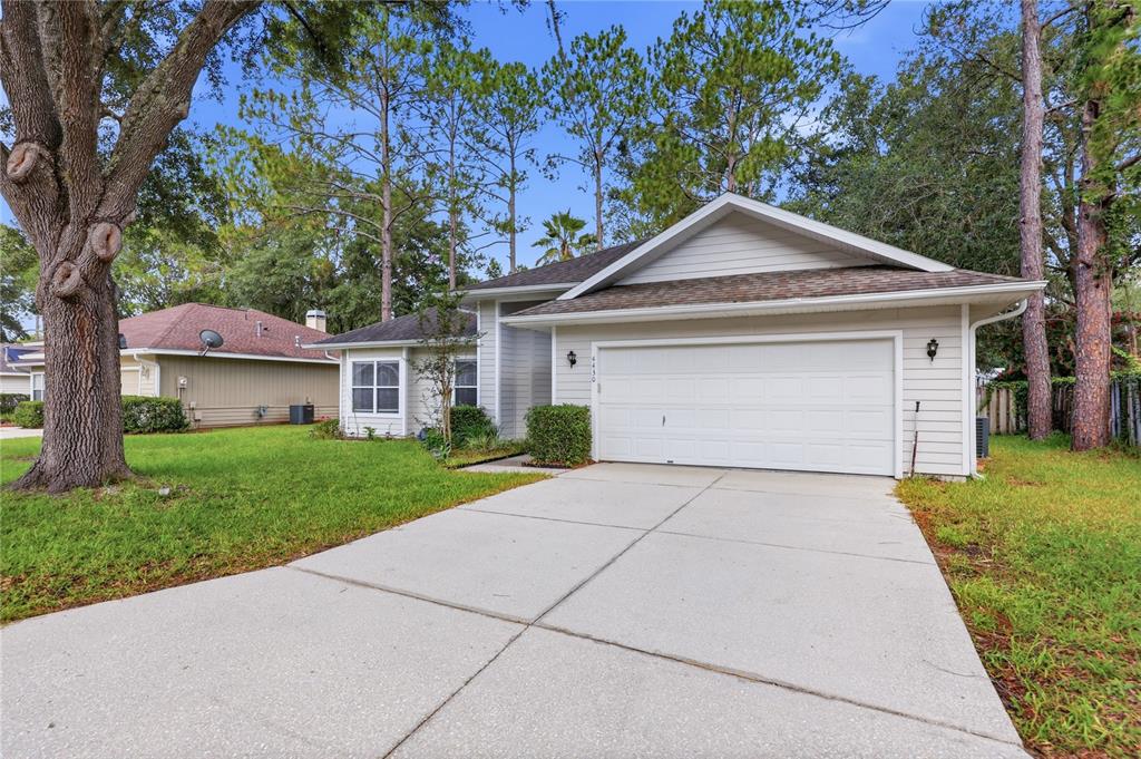 A single-story house with light siding, a two-car garage, and a concrete driveway — 4430 NW 35TH TERRACE, GAINESVILLE, FL